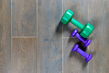 colored dumbbells in different sizes on gray floor with side space for text - Workout concept - Flat minimal design