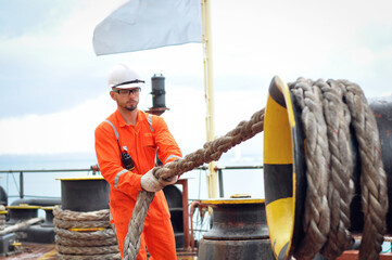 An experienced sailor in orange overalls and a white helmet works on a bulk carrier.
- 387998910