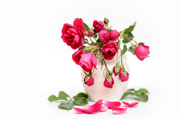 Obraz na płótnie Canvas red garden roses in a white vase on a neutral background