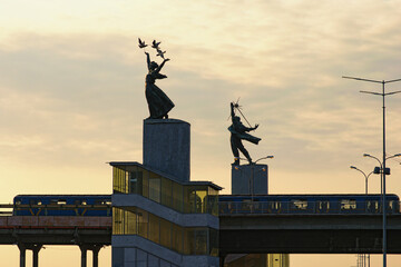 Kyiv, Ukraine-September 26,2020:Landscape view of Dnipro Metro Station at autumn sunrise. Station decorated by Sculpture Trud (Labor) and Sculpture Mir (Peace). The metro train stopped in the station