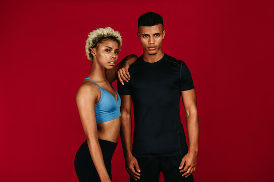 Fitness couple standing together on maroon background