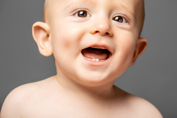 Adorable baby boy showing his first teeth, concept of caring for baby teeth, dental care