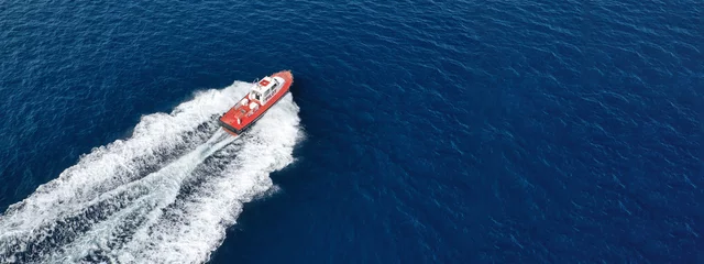 Fototapeten Aerial drone ultra wide photo of small pilot vessel cruising near mediterranean port with deep blue sea © aerial-drone