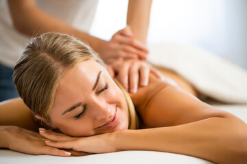 Fototapeta na wymiar Professional masseur doing therapeutic massage. Woman enjoying massage in her home. Young woman getting relaxing body massage.