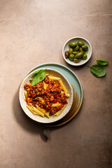 Overhead view of penne with bolognese sauce and basil leaves