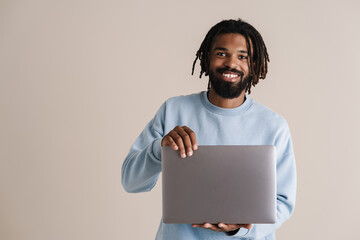 Happy african american guy smiling and holding laptop