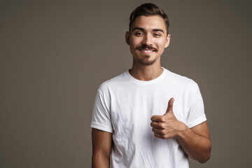 Image of joyful unshaven guy smiling and showing thumb up