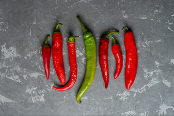 fresh chili peppers of red and green color evenly laid out on a concrete background.
