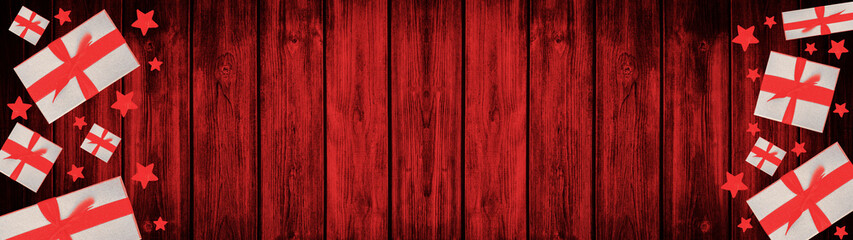 Festive Christmas / Advent background banner panorama - Top view / above view from gift boxes with red ribbon and stars, on rustic red wooden boards, wood table texture

