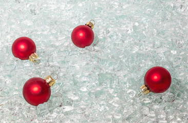 Red glass balls with gold hangers lie on glittering shards of glass