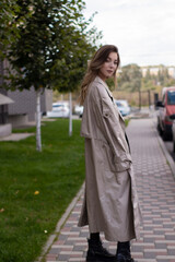 Fototapeta premium attractive slim young brunette in fashionable trench coat and black dress.