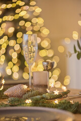 A glass of champagne in the background of the Christmas table and the lights of the Christmas tree