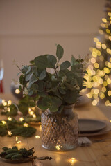 A glass of champagne in the background of the Christmas table and the lights of the Christmas tree