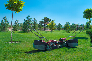 Two lawn mowers on the background of mown grass in the park.