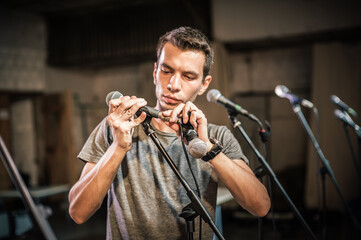 Theater audio technician adjusting an microphones on the scene. Installing and testing the sound system in the background