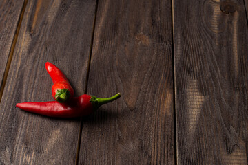 Two fresh chili peppers on a dark wood background, copyspace
