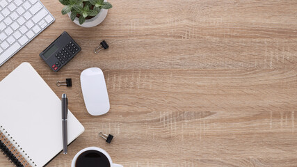 Top view wooden workspace office desk with computer and office supplies. Flat lay work table with blank notebook, keyboard, green leaf, calculator and coffee cup. Copy space for advertising content
