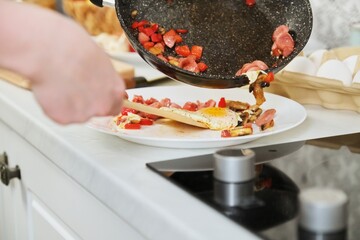 Homemade food, frying pan with scrambled eggs and paprika sausages on hob