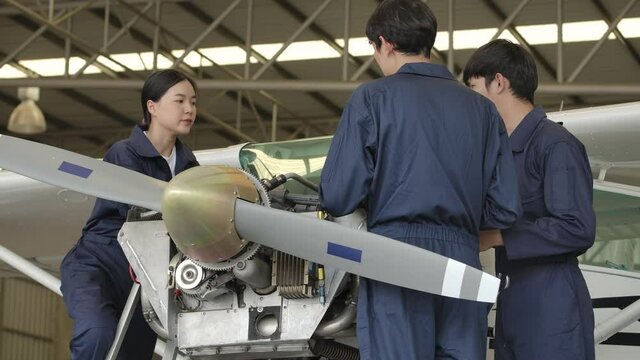 Group of young asian aviation maintenance engineer doing a pre flight checkup or maintenance on a small engine aircraft using digital tablet in hangar. Transportation and Technology concept.