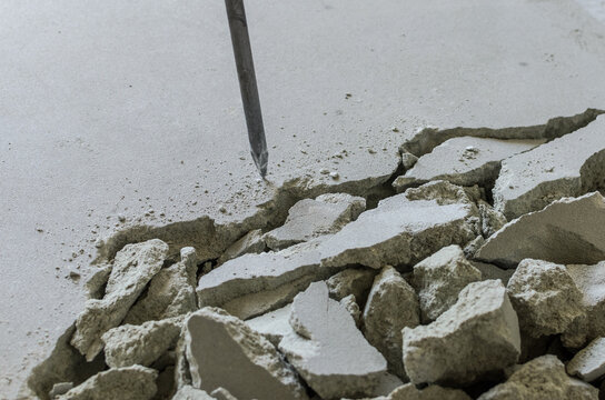 Worker smashes concrete floor with electric hammer drill