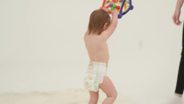 Happy little girl in diaper is playing toys. Slow motion