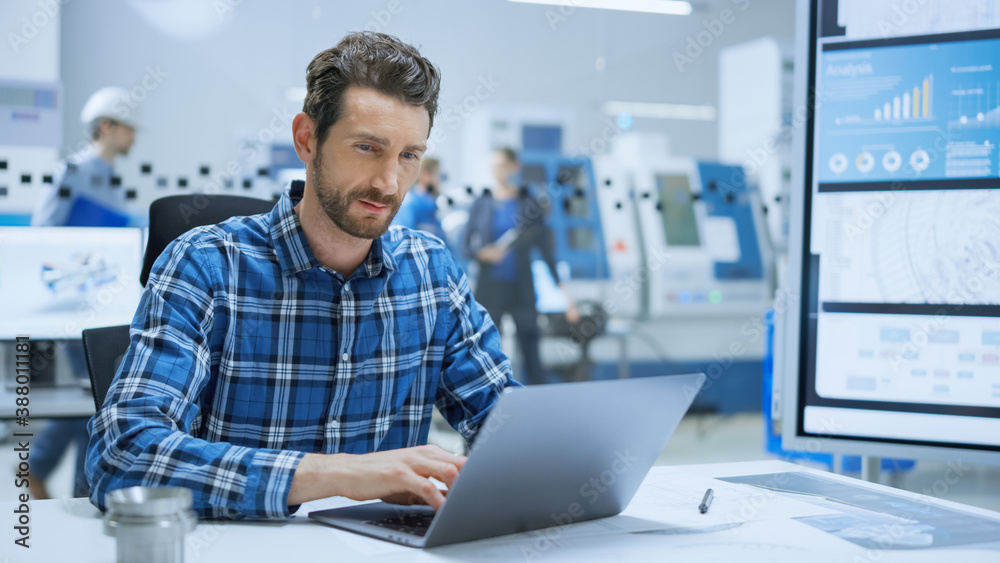 Aufkleber modern industrial factory: portrait of industry engineer sitting at his desk, working on laptop, ana
