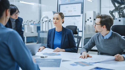 Modern Factory Office Meeting Room: Young Female Specialist Reports to Diverse Team of Engineers, Managers, Businesspeople and Investors Sitting at the Conference Table Analyzing Blueprints