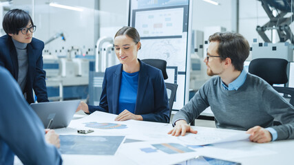 Modern Factory Office Meeting Room: Young Female Specialist Reports to Diverse Team of Engineers, Managers, Businesspeople and Investors Sitting at the Conference Table Analyzing Blueprints
