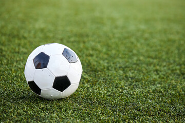 Fototapeta na wymiar football ball on fresh spring green grass, in the field, close-up