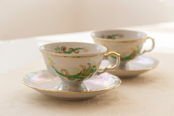 Two gold decorated tea cups built by a consecrated tablecloth.