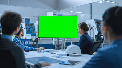 Modern Factory Office Meeting Room: Diverse Team of Engineers, Managers and Investors Talking at Conference Table, Watching Interactive TV that shows Green Screen Chroma Key Mock-up
