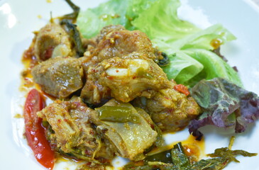 spicy fried pork bone with lettuce and green oak in curry sauce on plate 