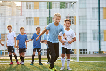 group of children practicing football on grass lawn. caucasian kids kicking soccer ball on primary...