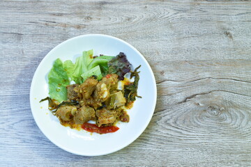 spicy fried pork bone with lettuce and green oak in curry sauce on plate 