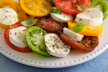 Caprese salad with mozzarella, colored tomatoes and fresh basil.