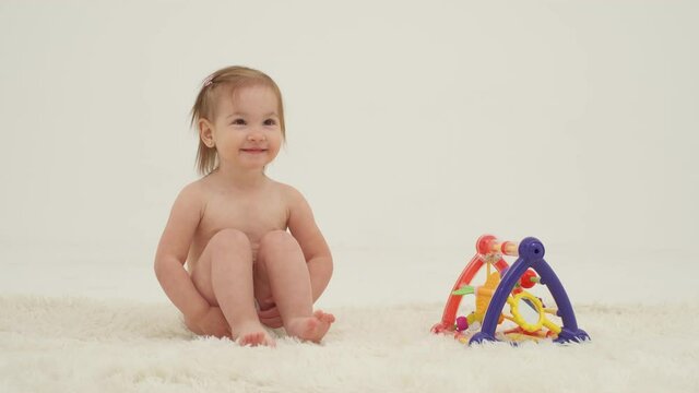 Happy little girl in diaper is playing toys. Slow motion