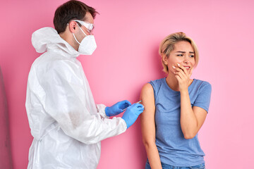 confident doctor with syringe doing injection vaccine,flu,influenza in the shoulder of young caucasian woman, healthcare concept