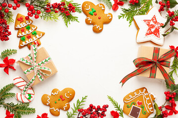 Christmas background with gingerbread cookies, gift boxes and branches of holly with red berries on white. Winter festive nature concept. Flat lay, copy space.