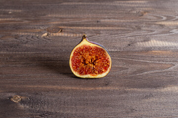 Half a fresh fig on an old dark dark wood table. Copy space flatlay on dark background.