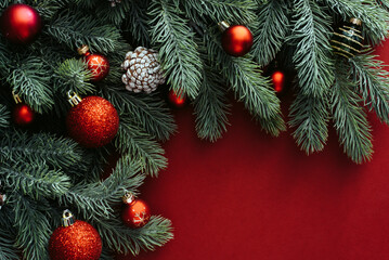 Space for text between Christmas tree branches with Christmas decorations and balls on a red background. Christmas composition. Happy New Year. Space for text