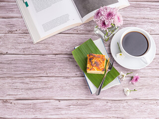 Thai custard cake (or Khanom mo kaeng) on a banana leaf on a white plate and a cup of white coffee...