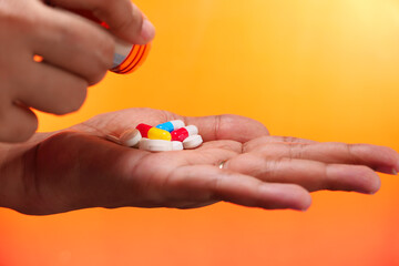 Close up of women hand taking pills on orange background 