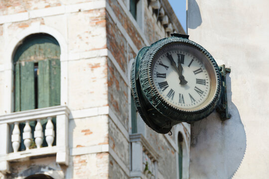 Vintage clock hanging outside on the corner of the house