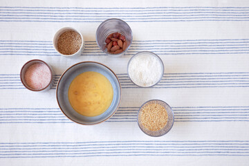 Ingredients in bowls, recipe for homemade bread. Baking at home, preparing dough, food on kitchen table. Real life flat lay shot.
