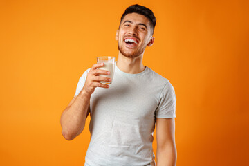 Happy smiling mixed-race man holding milk against yellow background