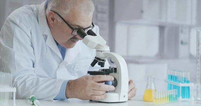 Microbiology Laboratory: Scientist Works with Various Bacteria. Concept of Pharmaceutical Research for Antibiotics, Curing Disease with DNA Enhancing Drugs. A man doctor with a microscope
