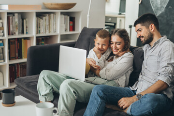 happy family relaxing on sofa at home and using computer