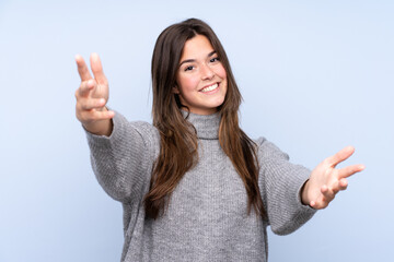 Teenager Brazilian girl over isolated blue background presenting and inviting to come with hand
