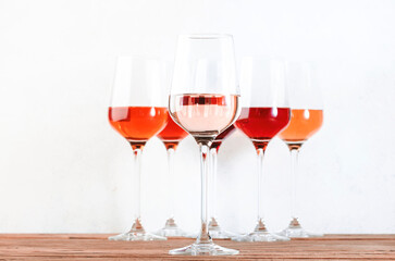 Rose wine glasses set on wine tasting. Tasting different varieties, colors and shades of pink wine concept. White background