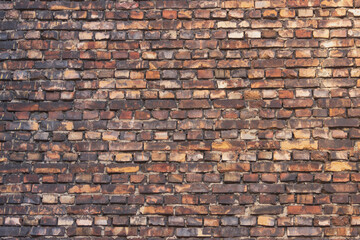 The old wall of the building is made of multi-colored bricks, darkened by time, smoked with soot.